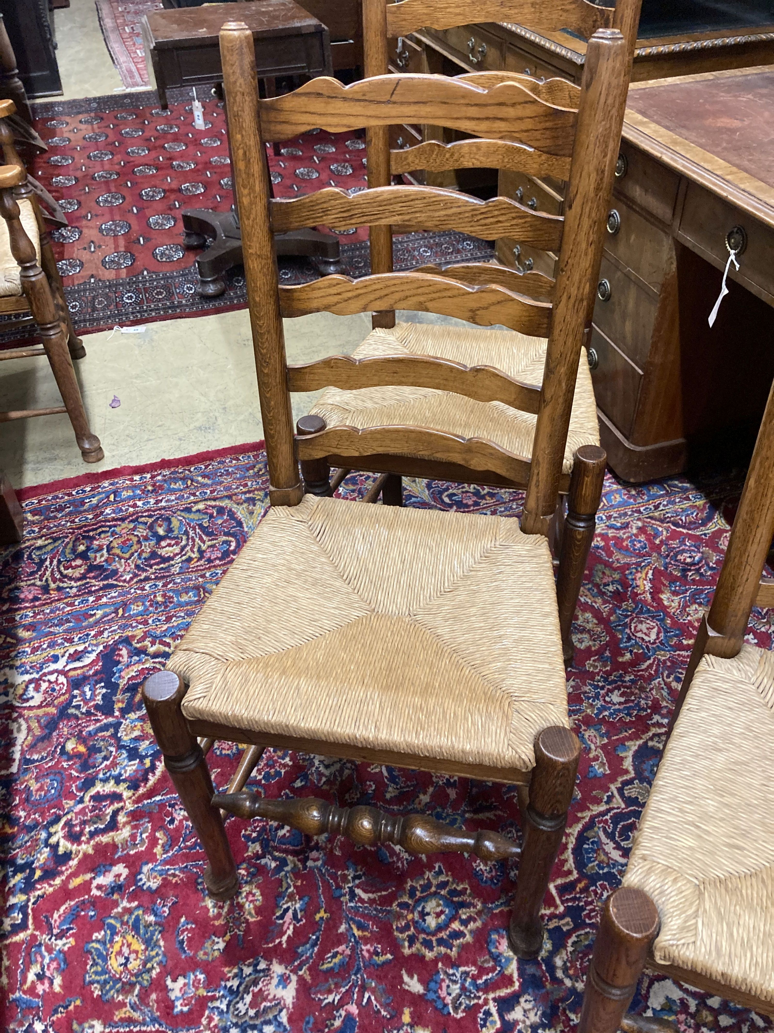 A set of eight 18th century style oak rush seat ladderback dining chairs, (two with arms)